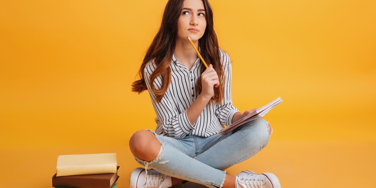 Portrait of a pensive young girl making notes
