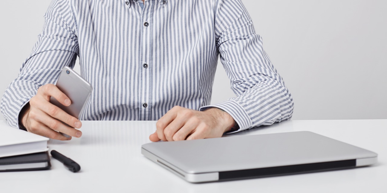 Candid shot of successful male with thick beard, uses modern technology for work, reads sms on cell phone, being glad, messages online uses free internet connection. People, business concept