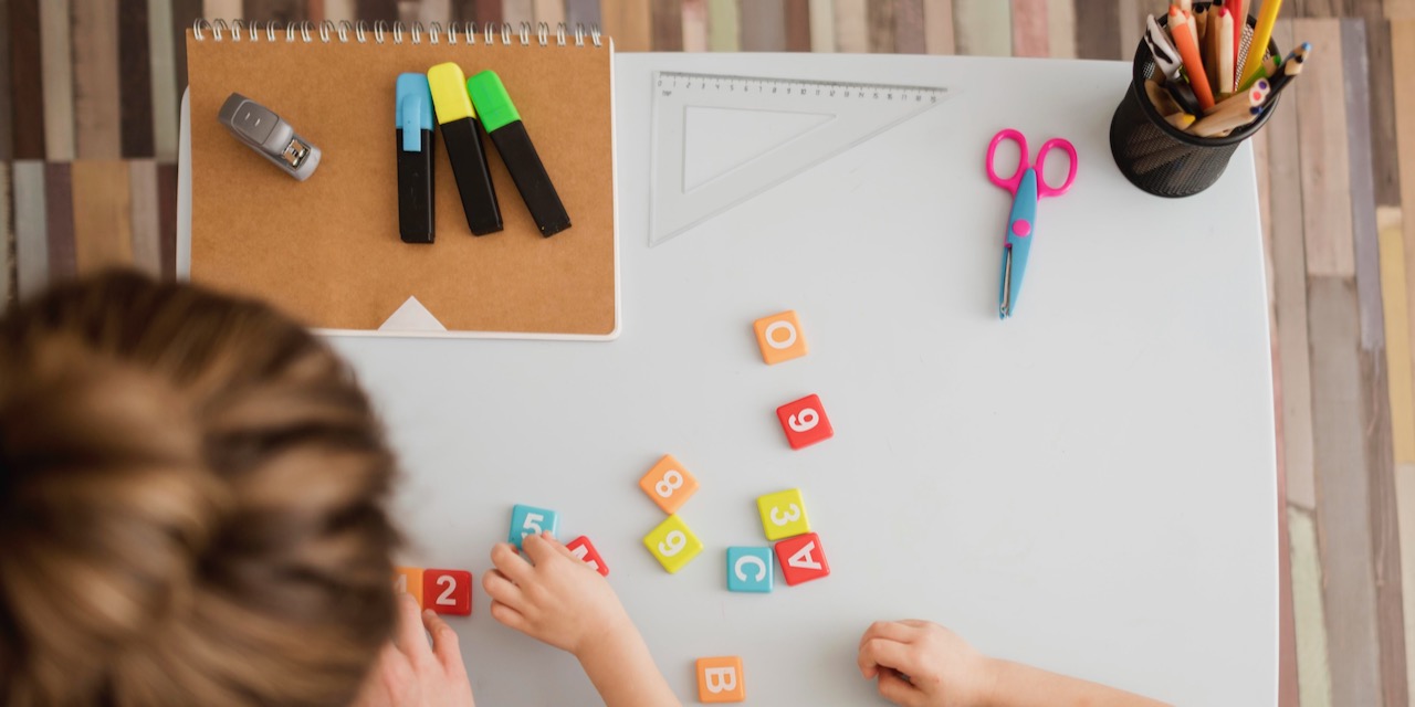 vista-dall-alto-di-bambino-e-tutor-che-imparano-numeri-e-lettere