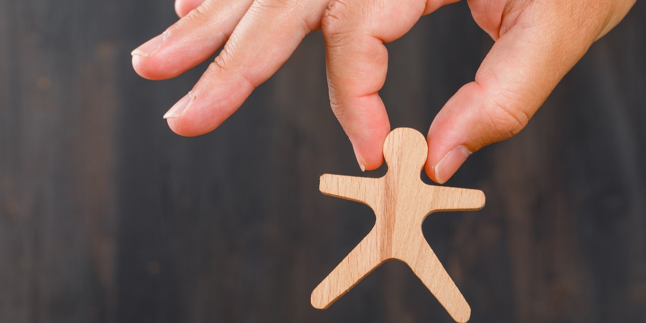 Business and target audience concept on blurry background side view. hand holding wooden human model.