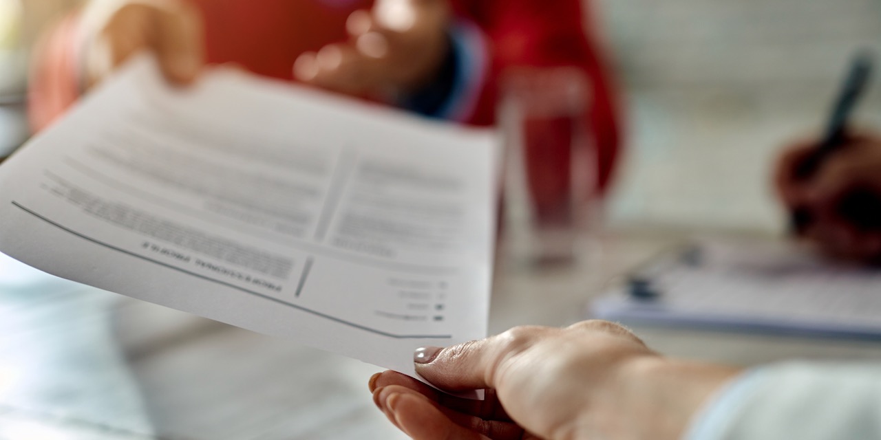 Close-up of a candidate giving his CV while applying for a job.