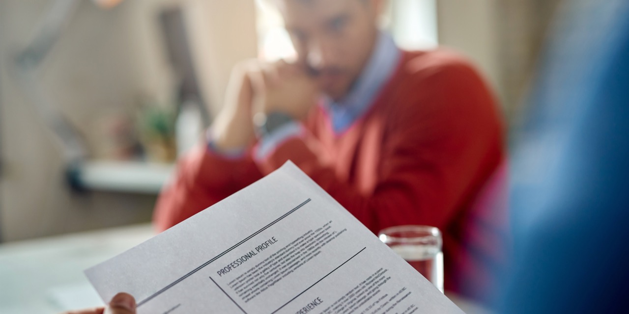 Close-up of a businessman reading candidate’s resume during a job interview.